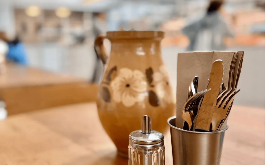 Una cafetera de barro cocido, un vaso de agua, tres dientes de ajo y una ramita de hiedra